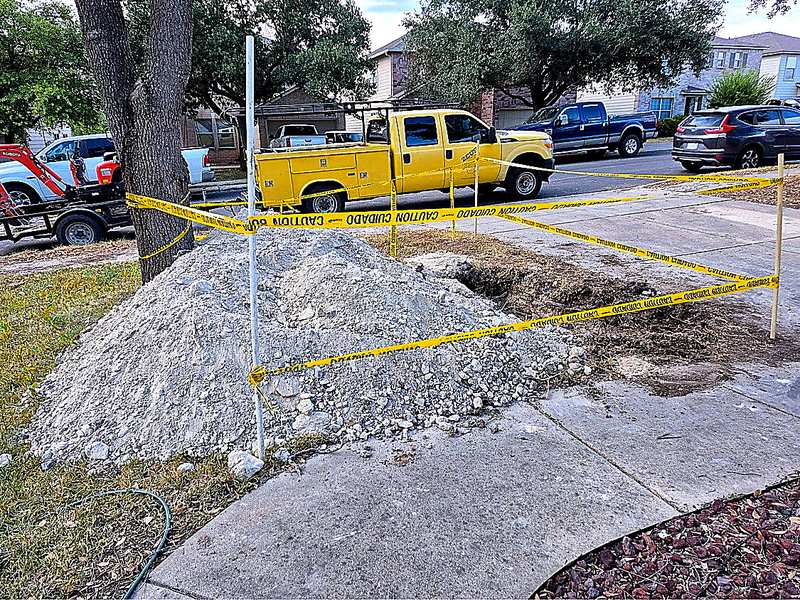 Zeus Plumbing yellow utility truck at a taped-off curb excavation for service-line access in San Antonio