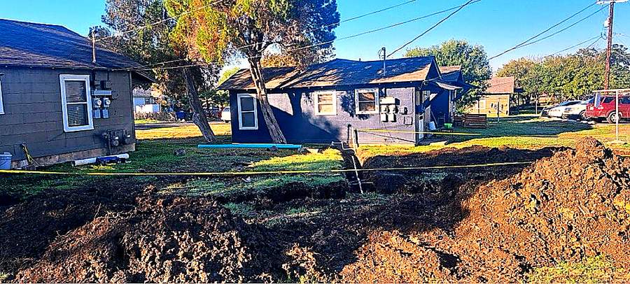 Sewer line replacement trench running from a San Antonio home